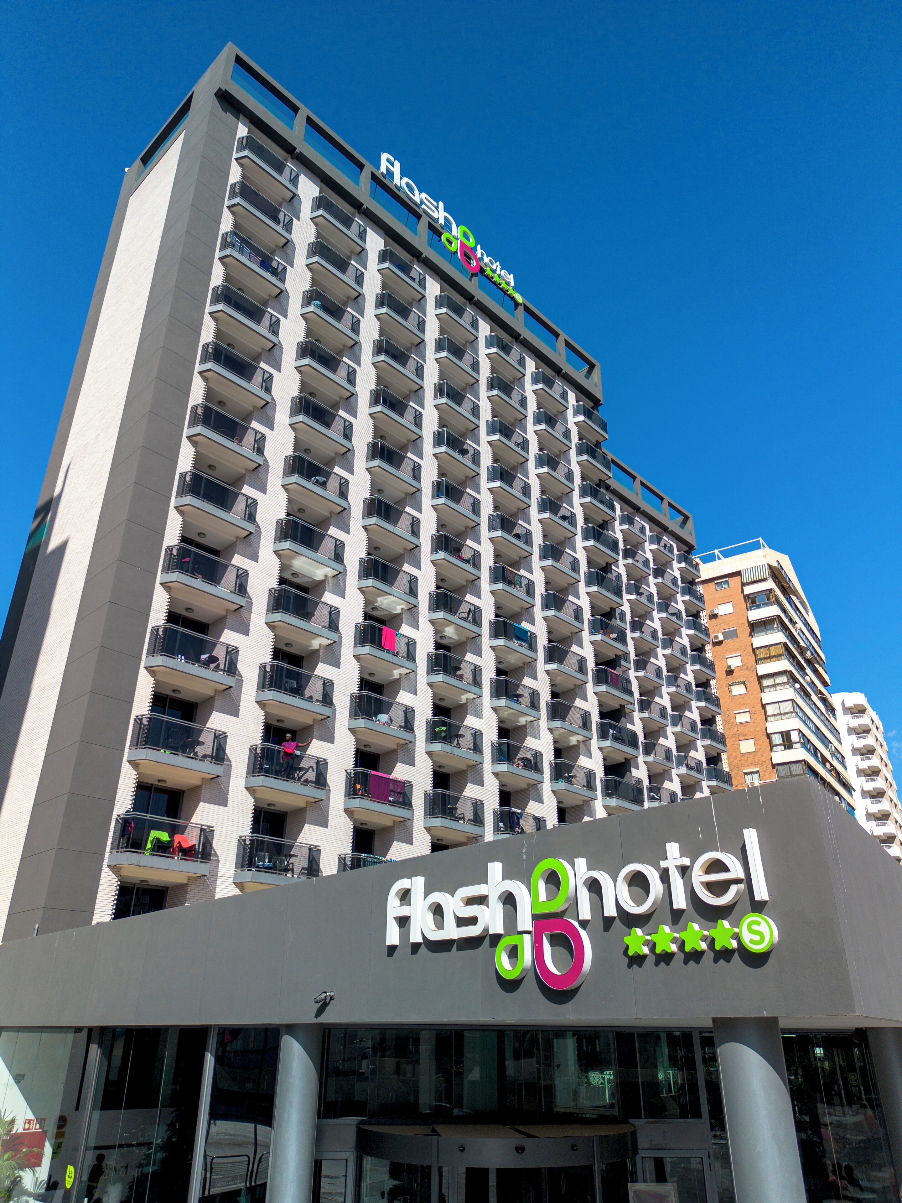 A high-rise hotel with multiple balconies, a prominent sign, and a clear blue sky.