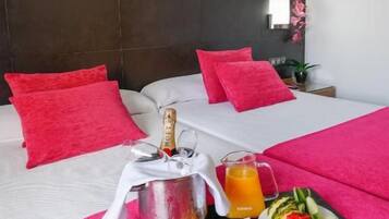 A hotel room with a bed, a breakfast tray, a bottle of champagne, and a painting of a person in a hat.