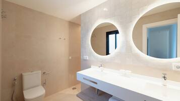 A modern bathroom with a toilet, a sink, and a shower.