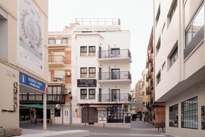 Un immeuble à plusieurs étages doté de balcons, d’un panneau d’information touristique et d’un restaurant appelé « D-VORA ».