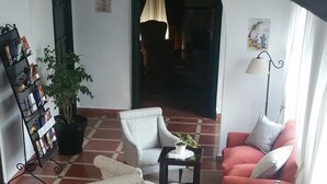 Een ruime woonkamer met gestreepte banken, een bijzettafeltje en een potplant.
