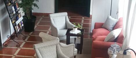 Un salón amplio con sofás estampados, una mesa de centro y una planta en maceta.
