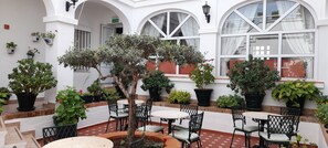 Un patio con plantas en macetas, asientos exteriores y una puerta que indica "SALIDA".