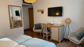 Habitación de hotel con dos camas, un escritorio con silla, televisión y lámpara de pie.