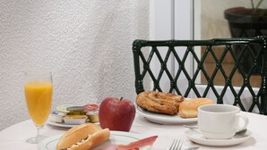 Een ontbijttafel met eten op een bord, een glas sinaasappelsap, een kop en een vork.