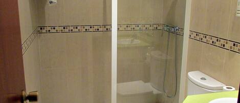 Une salle de bain avec une douche à parois de verre, des toilettes et un lavabo.