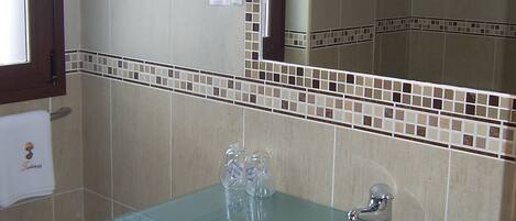 A bathroom with a glass sink, a toilet, and a mirror.