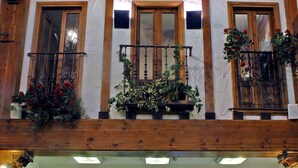 A hotel lobby with a wooden ceiling, a reception desk, and a balcony with potted plants. - Hotel Tudanca Aranda II (Fuentespina)