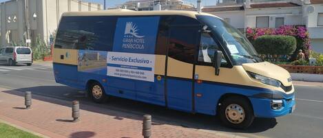 Una furgoneta azul y beige con la leyenda "GRAN HOTEL PENÍSCOLA" y "Servicio Exclusivo" en la carrocería, estacionada en una calle.