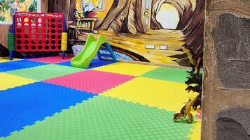 A play area with a colorful floor, a slide, and a mural.
