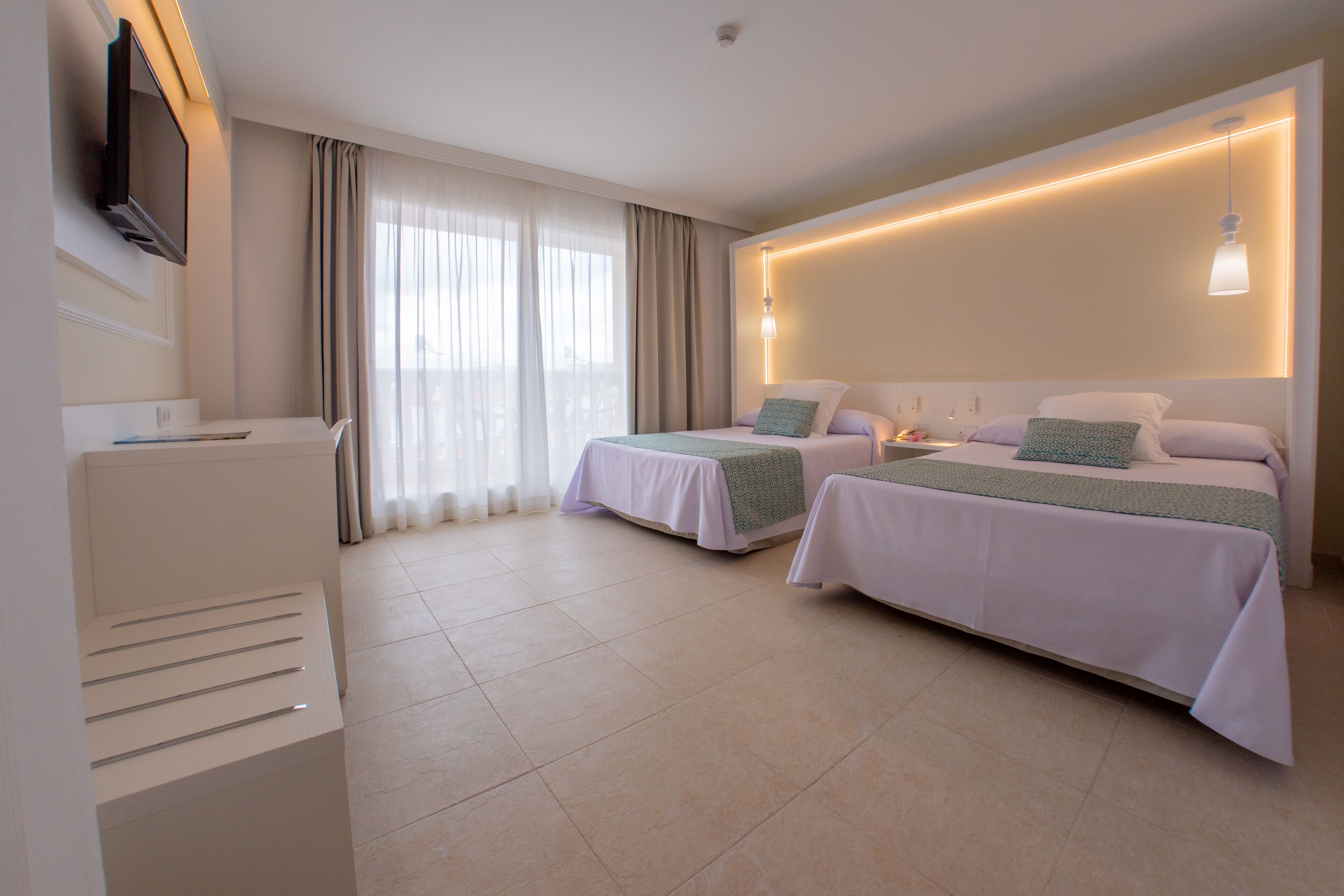 A hotel room with two beds, a TV, and a minibar.