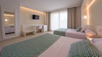 Habitación de hotel con dos camas, un escritorio, un televisor y una ventana con cortinas.