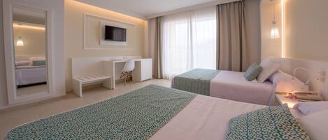 A hotel room with two beds, a desk, a TV, and a window with curtains.