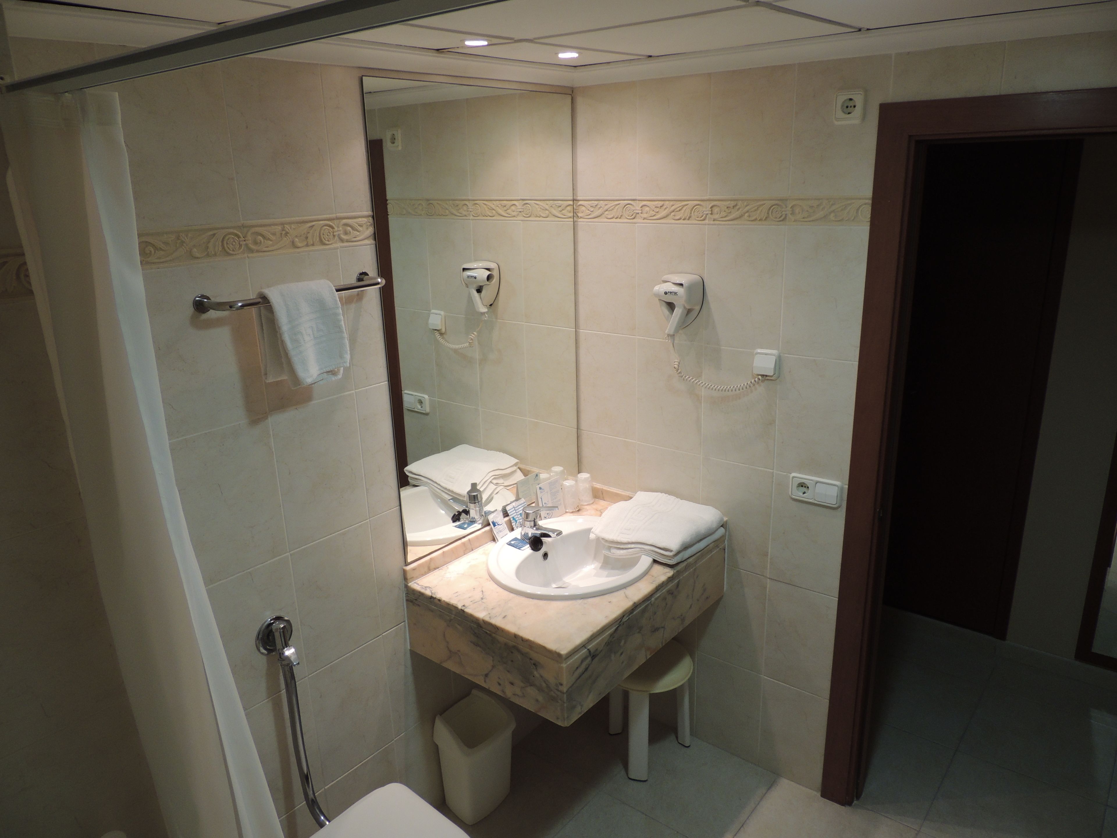Une salle de bain avec un lavabo en marbre, des toilettes, une douche et un porte-serviettes.
