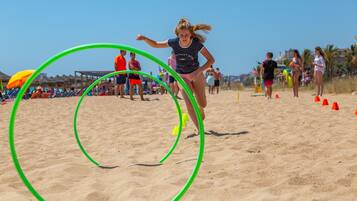Una playa con gente, incluyendo a una mujer corriendo entre aros verdes.