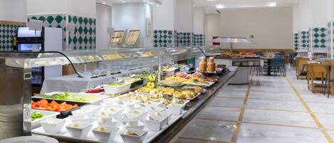 A buffet with various food items and a seating area with tables and chairs.