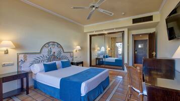 A hotel room with a large bed, a ceiling fan, a TV, and a mirror.