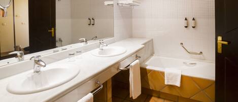 A modern bathroom with two sinks, a large mirror, a bathtub, and a tiled floor.