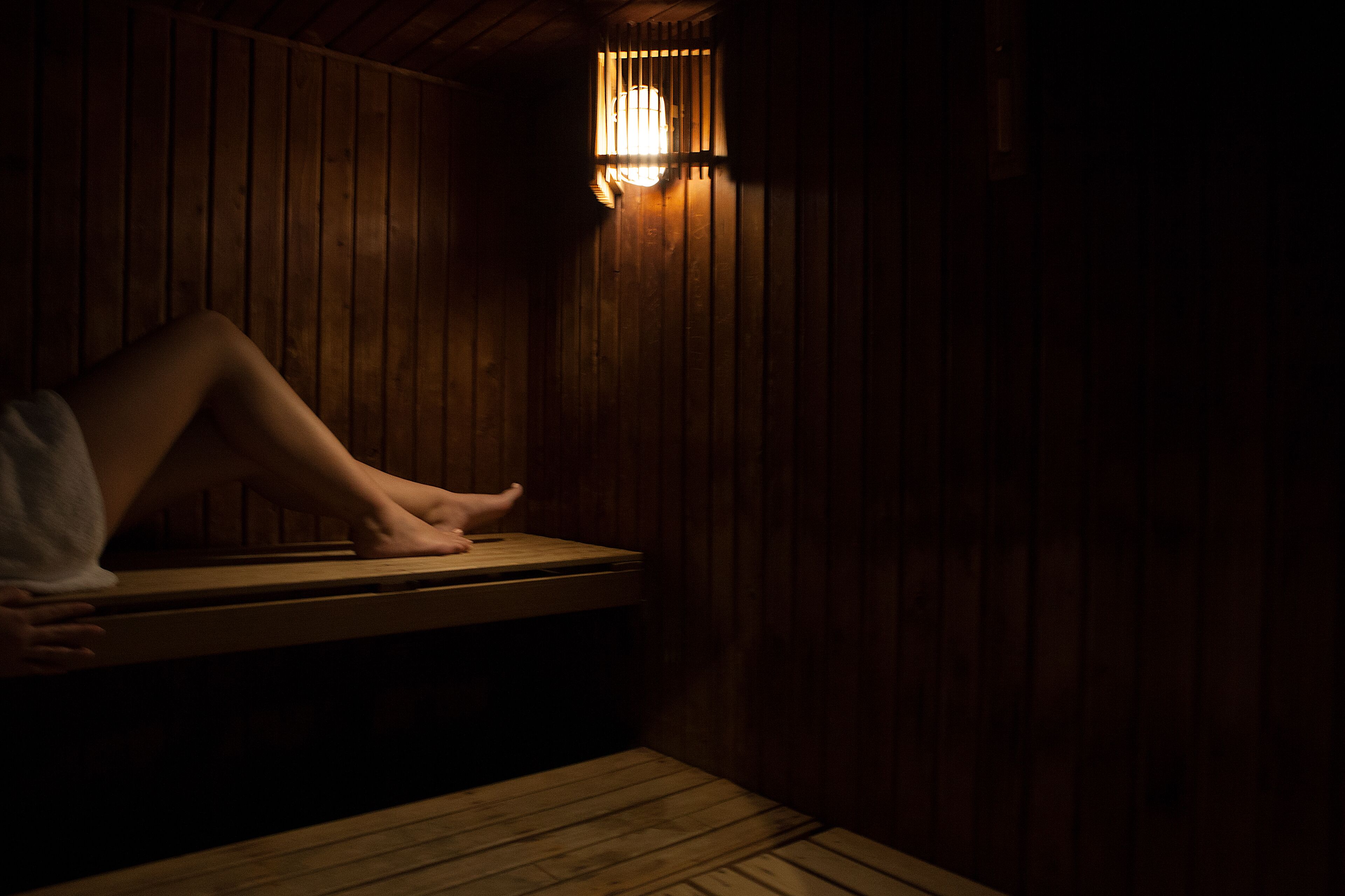 A wooden sauna with a bench and a light fixture above it.