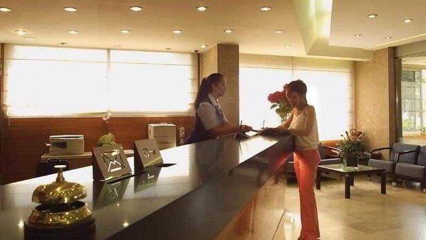 A reception area with a receptionist, a counter with a laptop, and a window with a view. - Maritim (Roses)