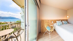 A balcony with a view of the sea, a bed with pillows, a chair, and a table. - Maritim (Roses)