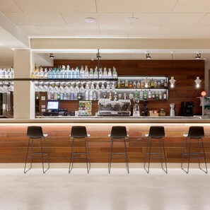 A bar area with multiple stools, a counter with various bottles, and a coffee machine.