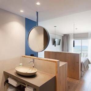 A modern bathroom with a round sink, a mirror, and a wooden partition.