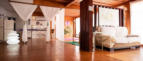 A spacious room with a wooden ceiling, a beige sofa, and a large window with a view of the outdoors.