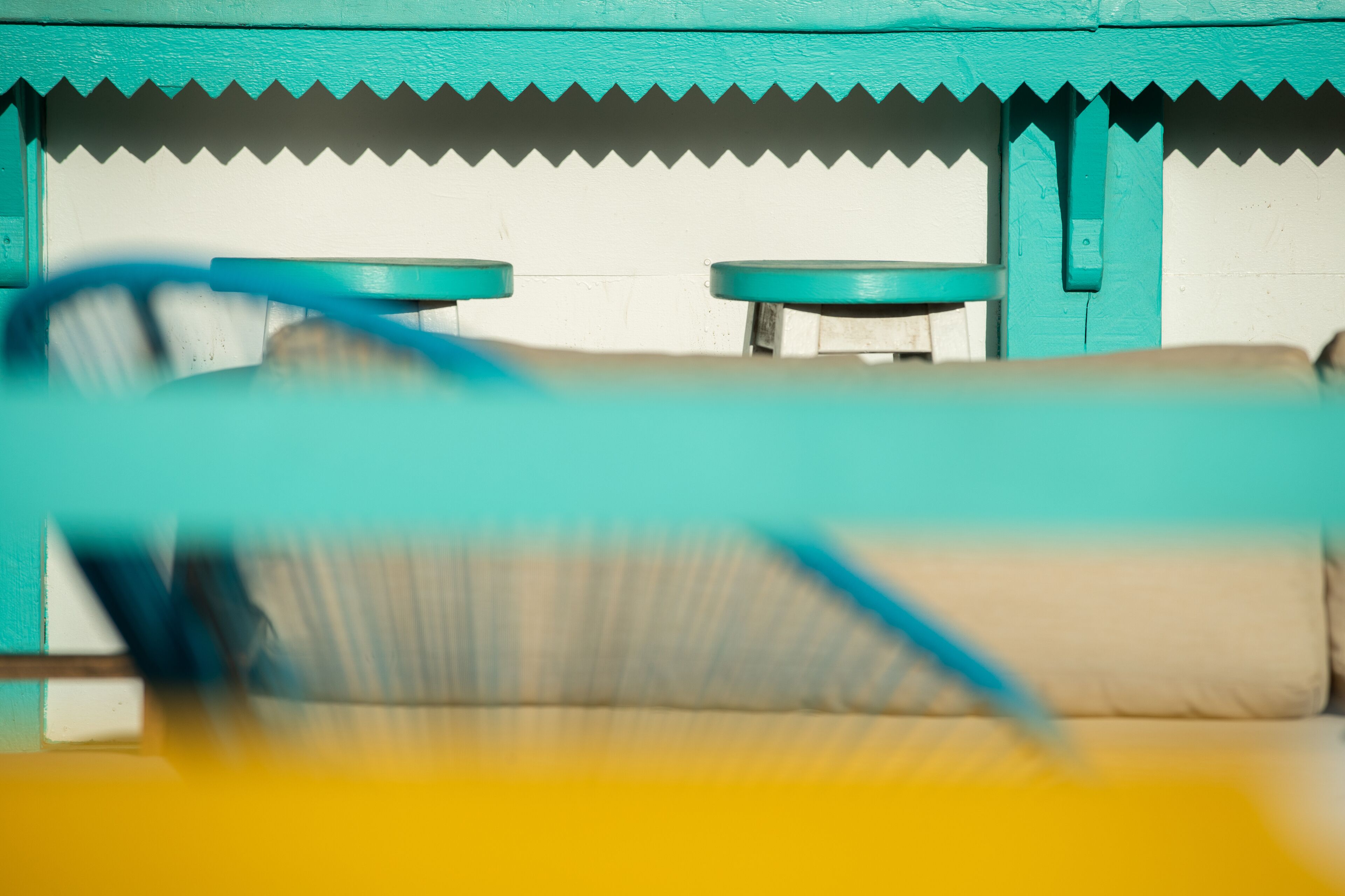 Una habitación con pared blanca y detalles en color turquesa, que incluye dos mesitas redondas y un sofá.