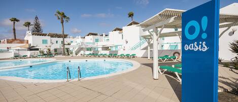 A pool area with a sign reading "O! oasis" and a clear blue sky.