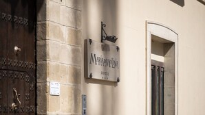 Un letrero de 'Maripolina Hotel' en un edificio con pared de piedra y puerta de madera.