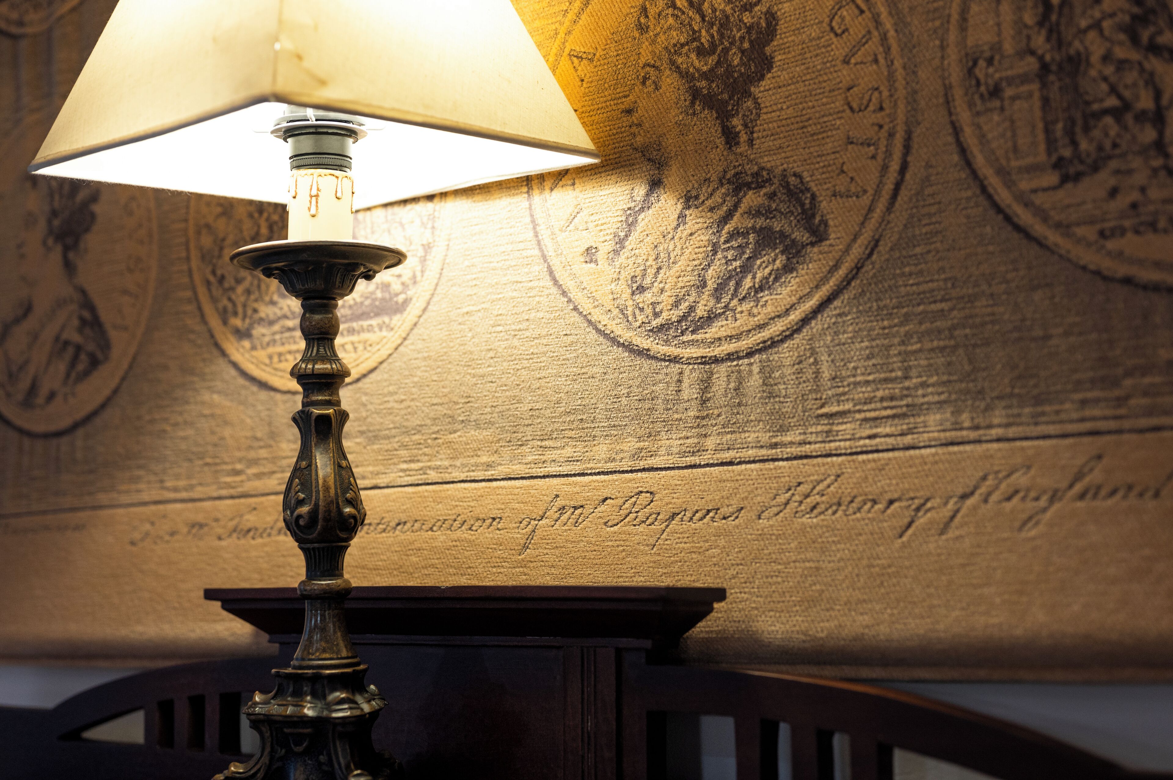 A lamp with a white shade on a wall with embossed text.
