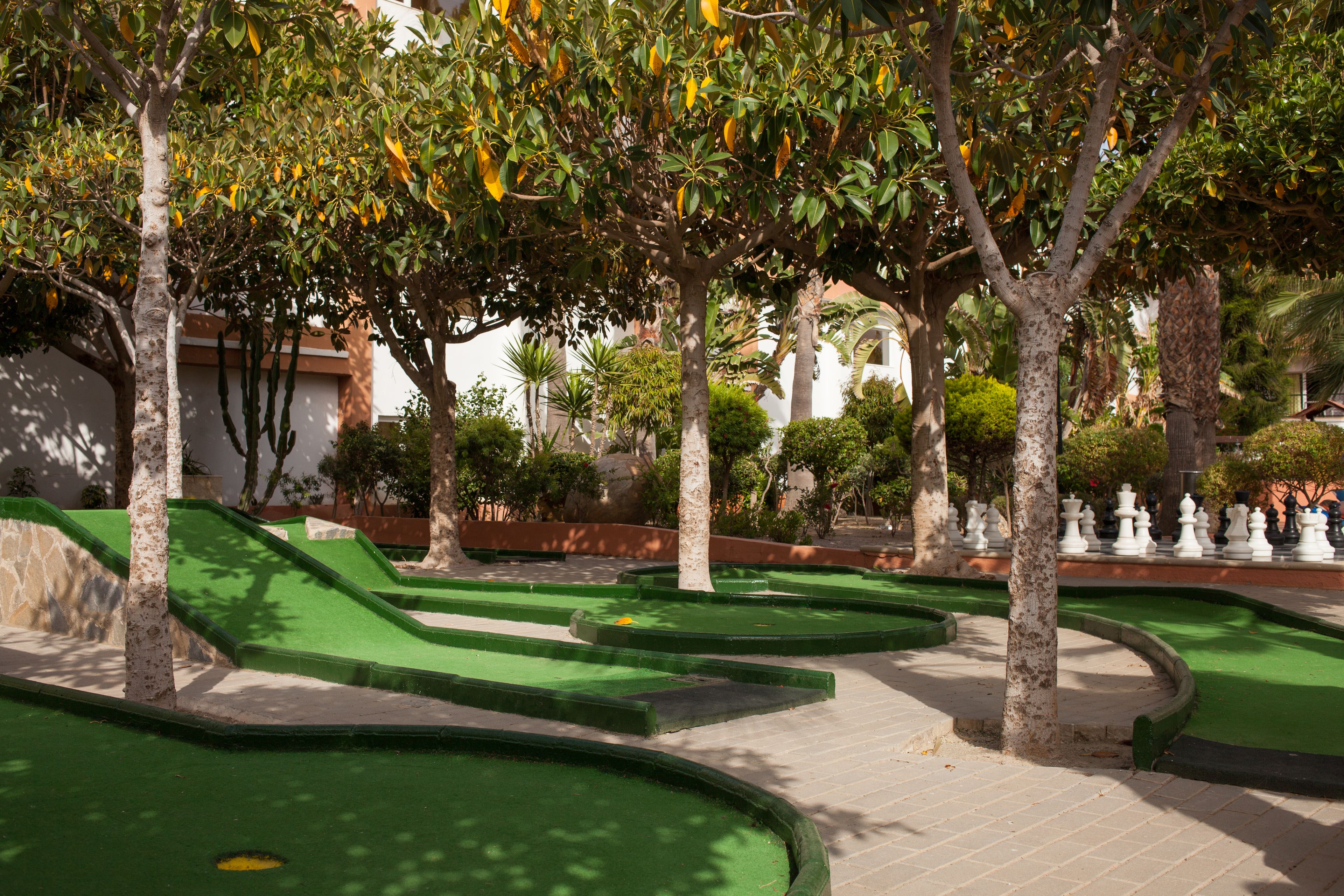 Un campo de mini golf con zonas de juego verdes y porta pelotas blancos.