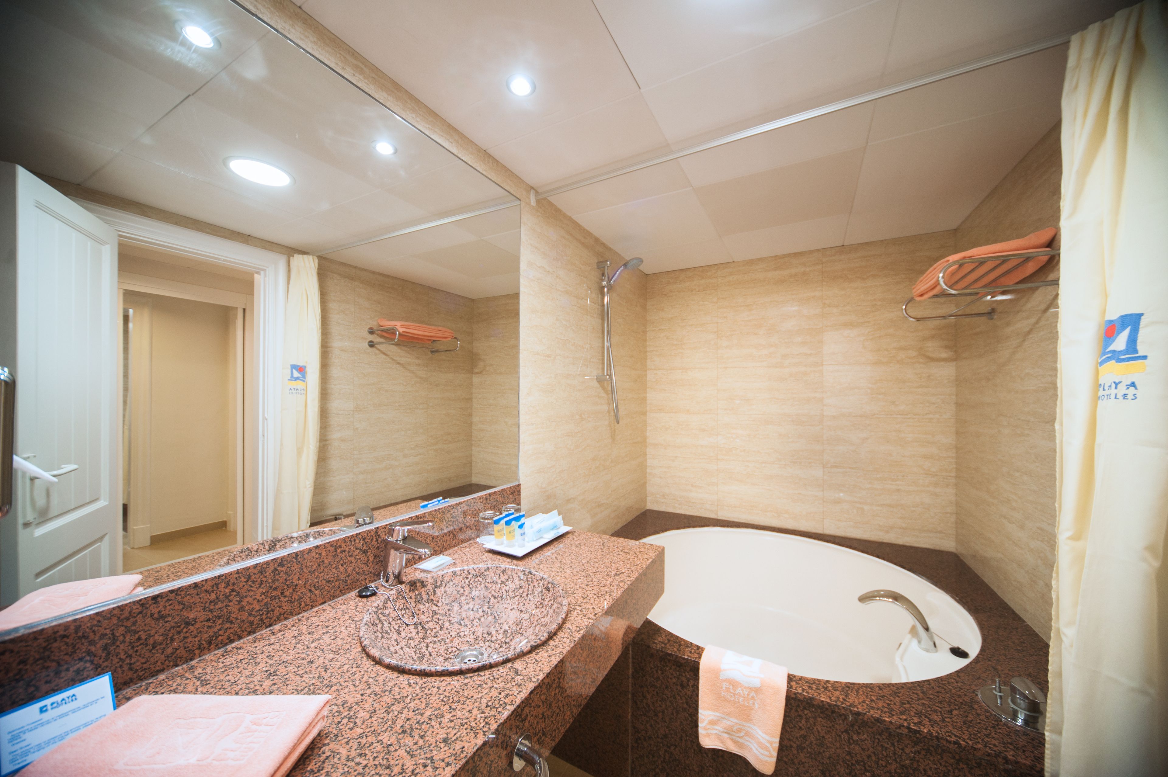 Un baño con encimera de granito, lavamanos, espejo, ducha y toallero.