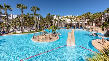 Una piscina techada, una piscina al aire libre, sombrillas