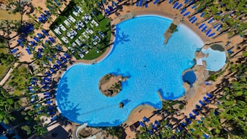 Una piscina techada, una piscina al aire libre, sombrillas