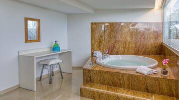Un baño moderno con una bañera independiente, encimeras de mármol, un perchero y un estante pequeño con artículos de aseo.