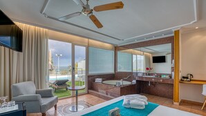 A hotel room with a bed, a sitting area with a chair and table, a bathroom with a bathtub and sink, and a large window with a view of the outdoors. - Playavera Hotel - Naturist Friendly (Vera)