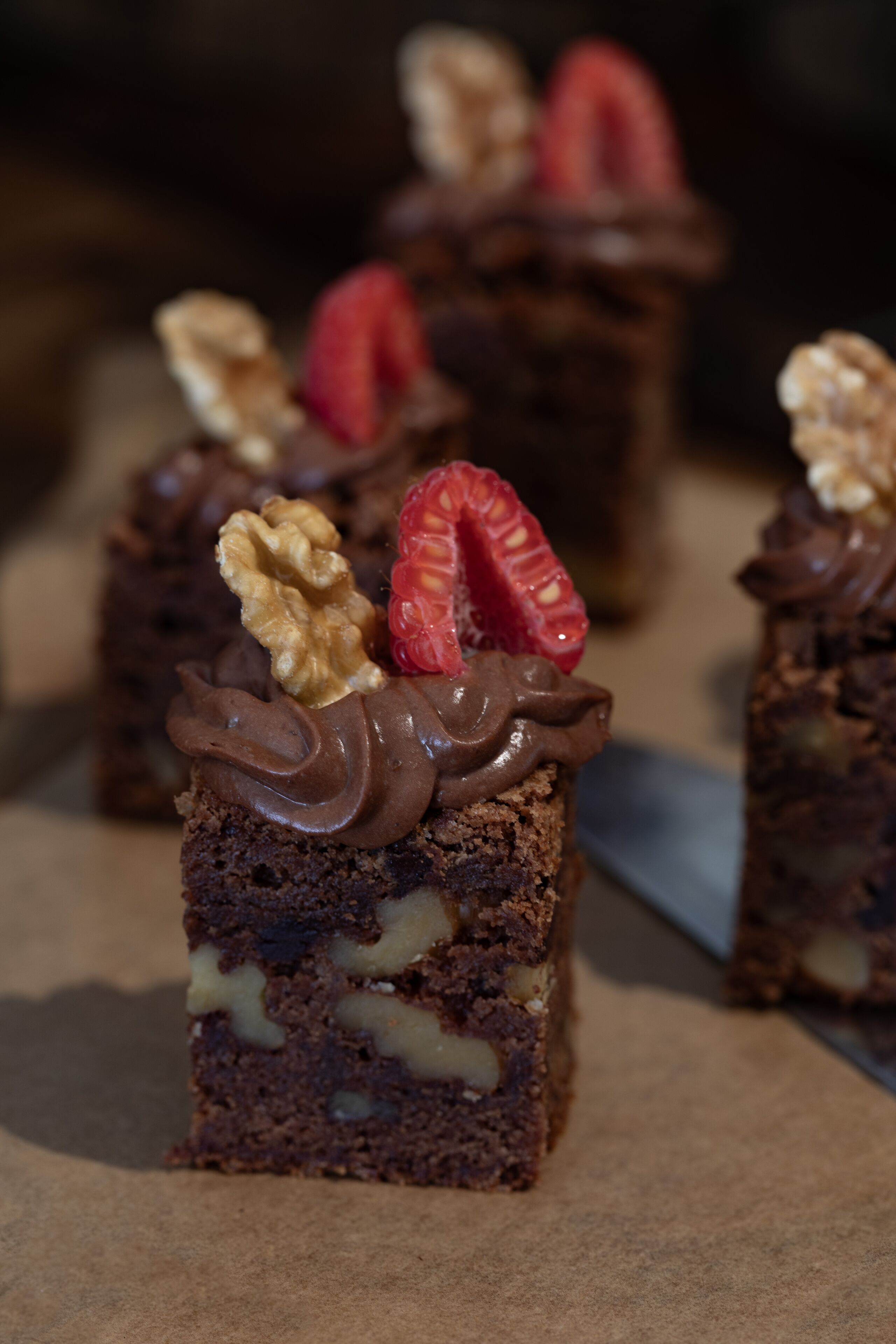A close-up of a chocolate dessert with walnuts and strawberries on top.