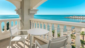 A balcony with a table and chairs, overlooking a beach and a rocky breakwater. - GRAN HOTEL LAS FUENTES (Alcala de Xivert)