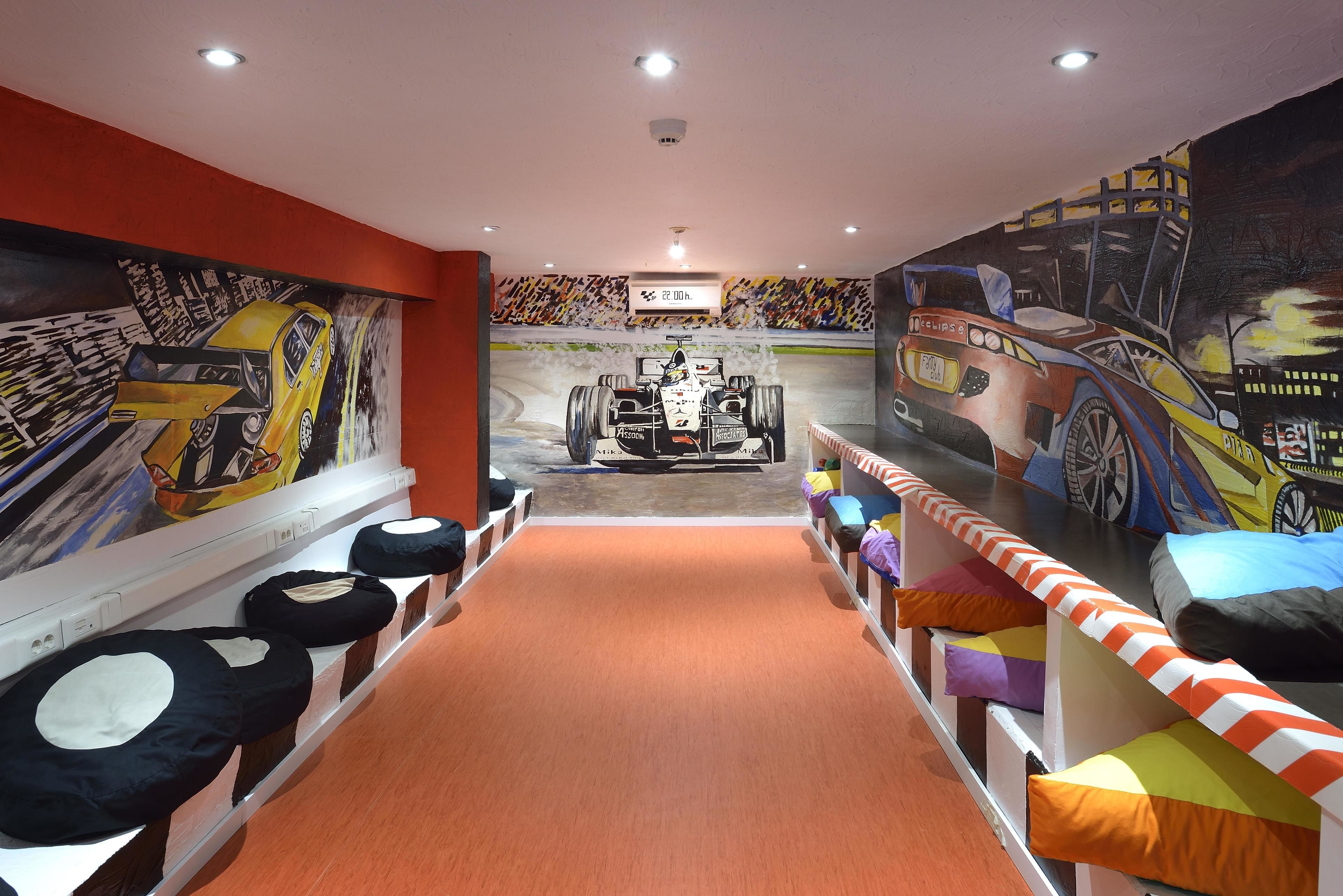 A children's play area with a race track theme, including a mural of a racing car and a track.