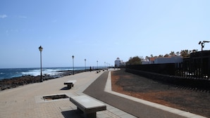 A coastal promenade with benches, street lamps, and a view of the ocean. - Puerto Caleta (Antigua)