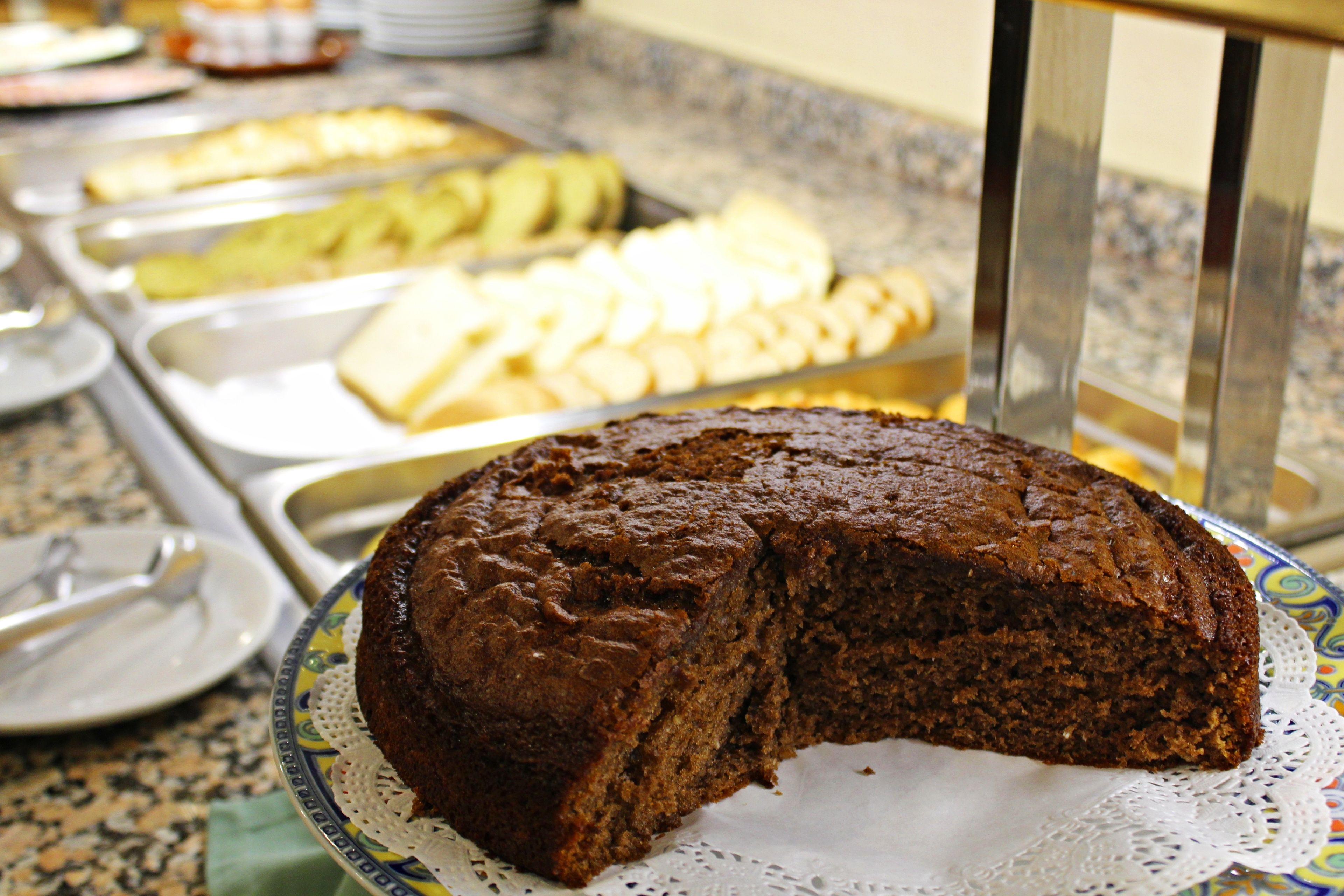 A buffet with various food items including a large piece of cake on a plate.