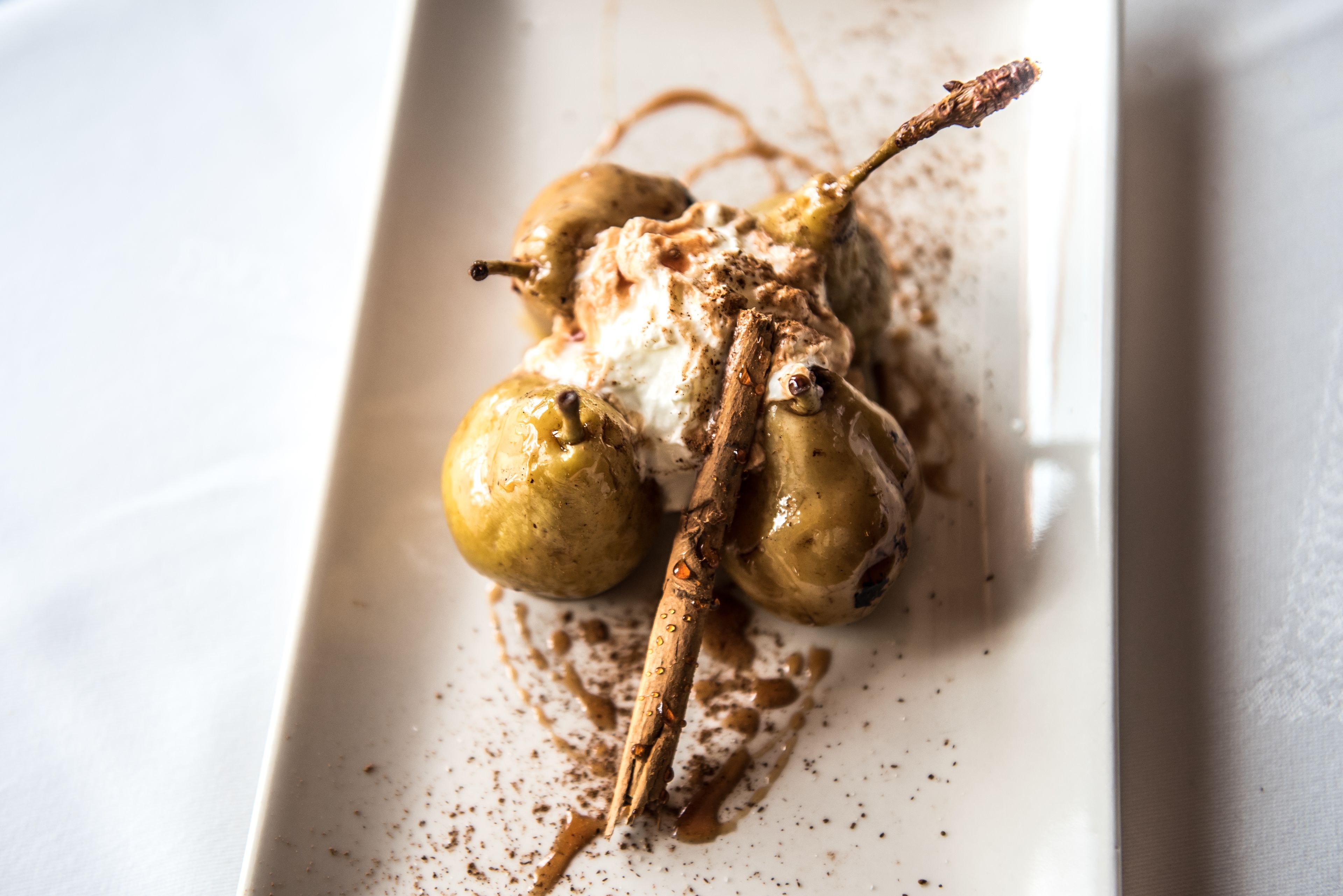 Un postre con peras y chocolate sobre un plato blanco.