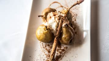 Un postre con peras y chocolate sobre un plato blanco.