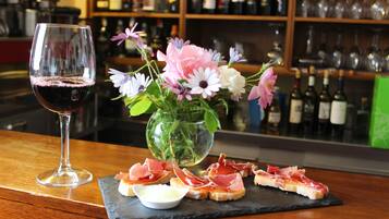 Een barsetting met een glas rode wijn, een vaas vol bloemen en een schoolbord met parmaham en kaas.