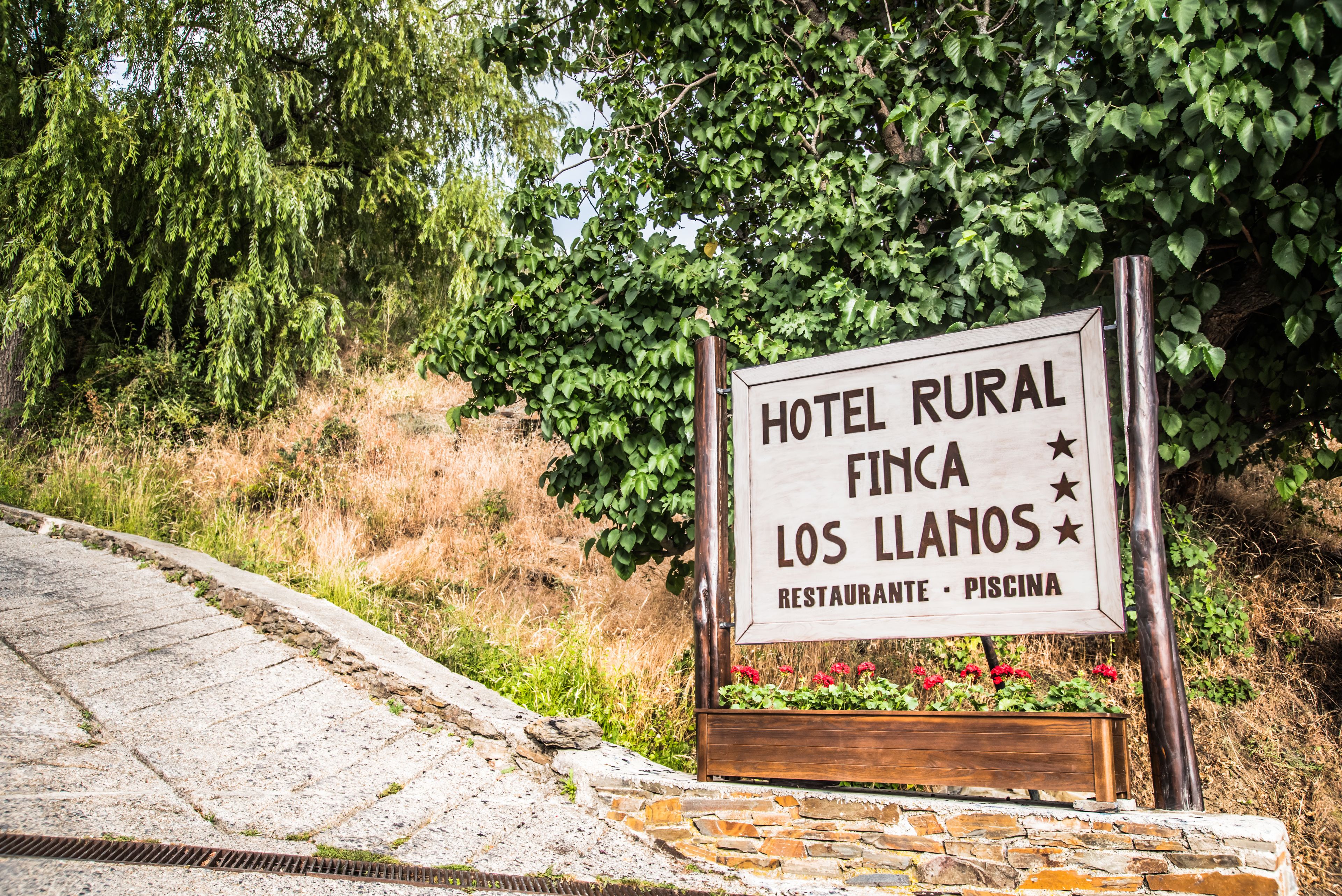 A sign for Hotel Rural Finca Los Llanos, indicating it offers a restaurant and a pool.