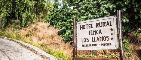 A sign for Hotel Rural Finca Los Llanos, indicating it offers a restaurant and a pool.