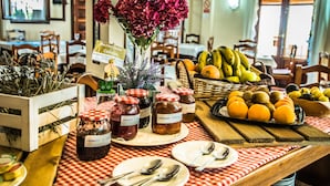 Een tafel met verschillende soorten eten, waaronder potten jam, verse bloemen en een mand vol fruit.