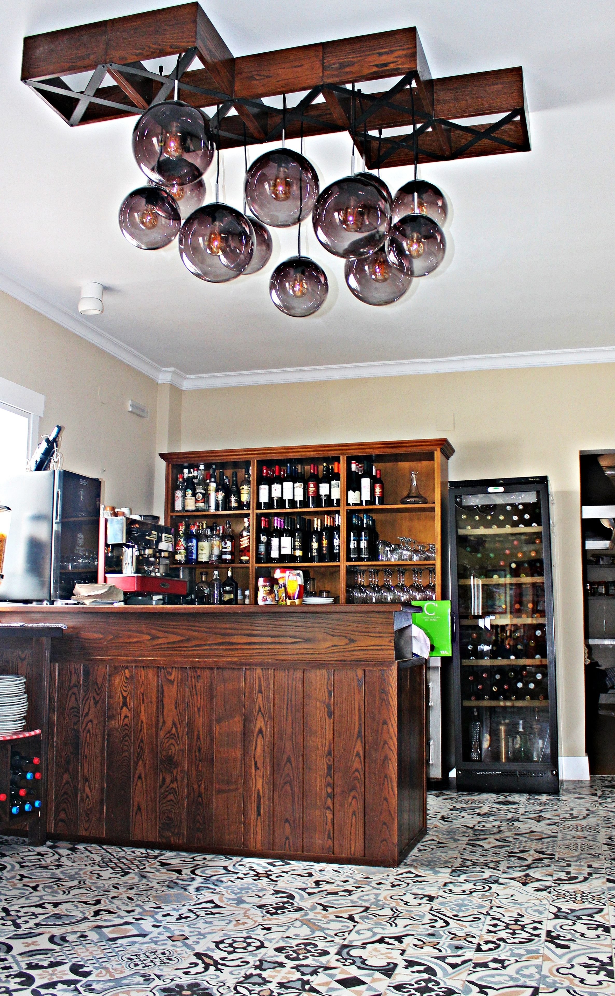 A bar area with a wooden bar counter, a wine rack, and a refrigerator.